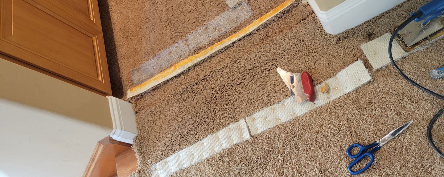 Carpet seam being trimmed and reconstructed after stretching by Ardent Carpet Restore